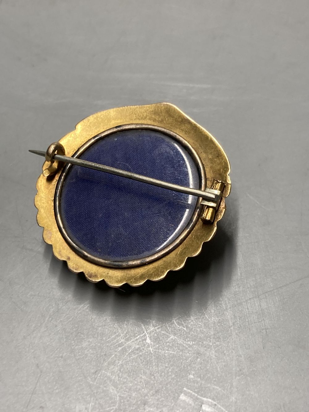 An early 20th century yellow metal (tests as 15ct) shell brooch, with glazed back, width 37mm, gross 10.3 grams.